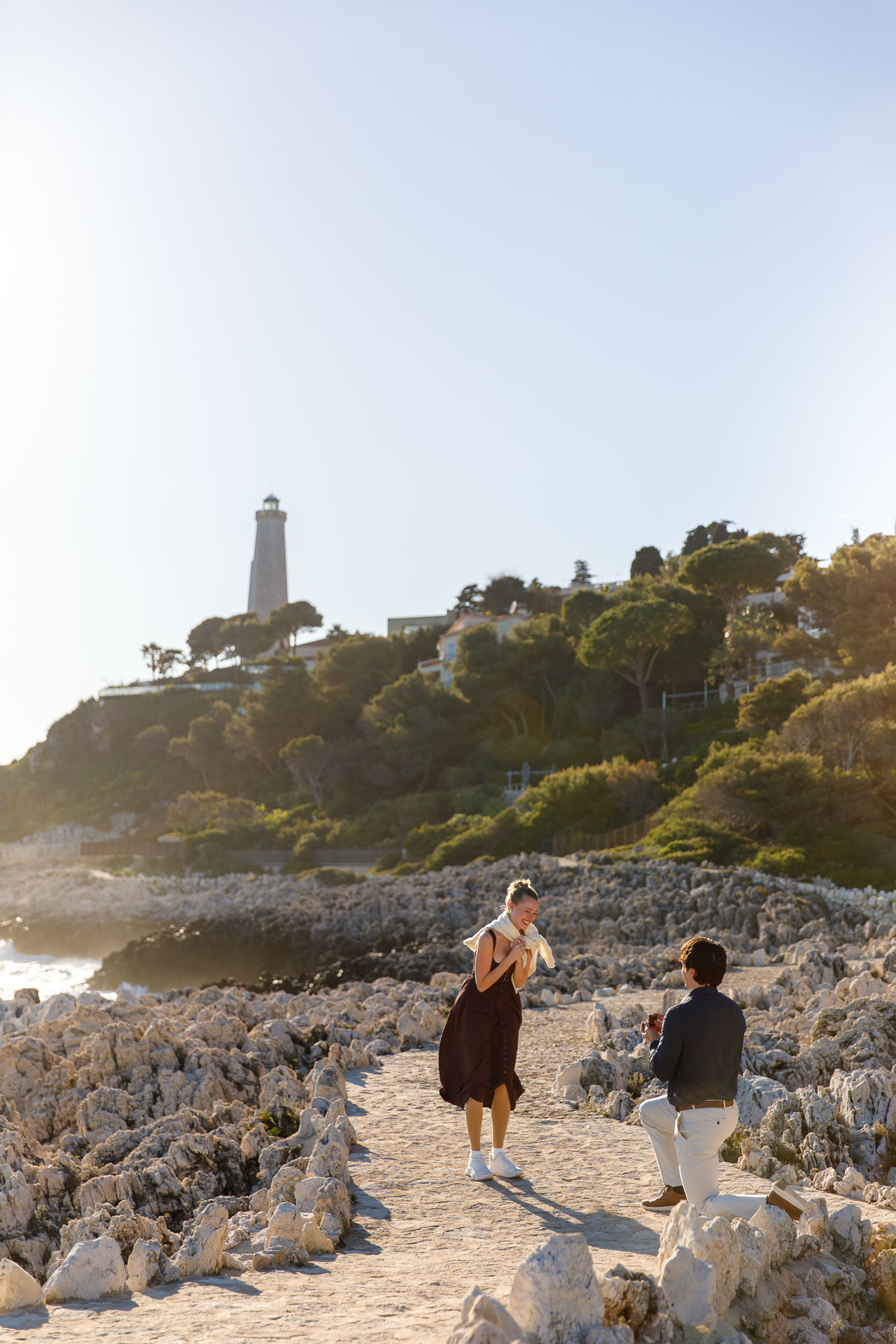 Surprise marriage proposal on the rocky coast of Saint-Jean-Cap-Ferrat at sunset with the Mediterranean Sea in the background